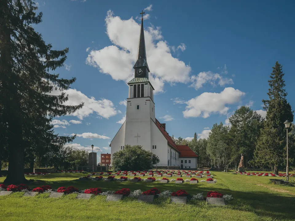 The wooden church at Kemijarvi standing among birches under a wide summer sky