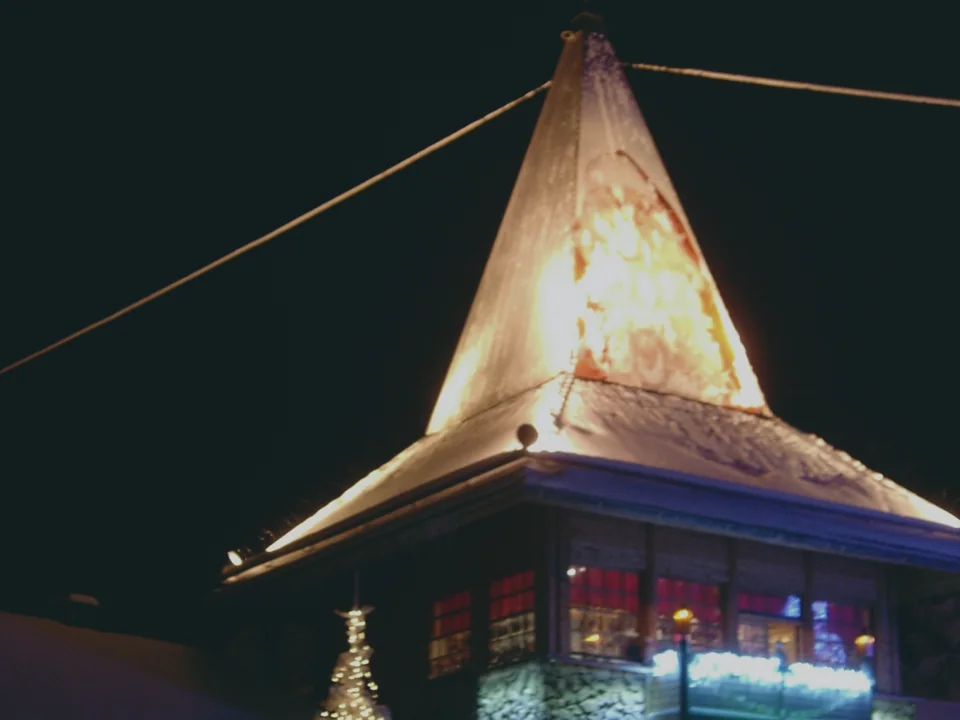 The spired main building of Santa Claus Village in Rovaniemi, lit against the night sky, in December
