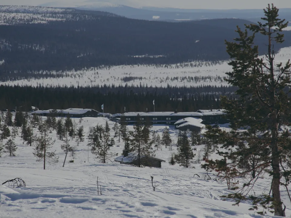 Hotel Pallas and the Pallastunturi visitor centre among snowy pines, with Ylläs fell on the horizon, in March
