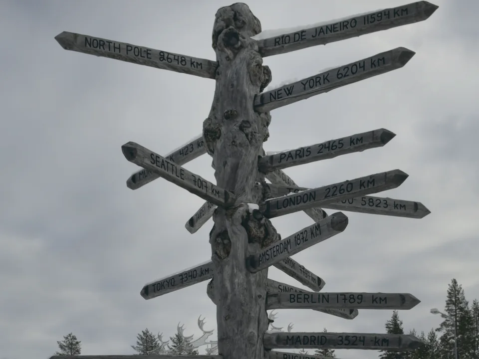A wooden distance pole outside Rovaniemi Airport, its arms pointing to the North Pole, London, Paris and other cities, in March
