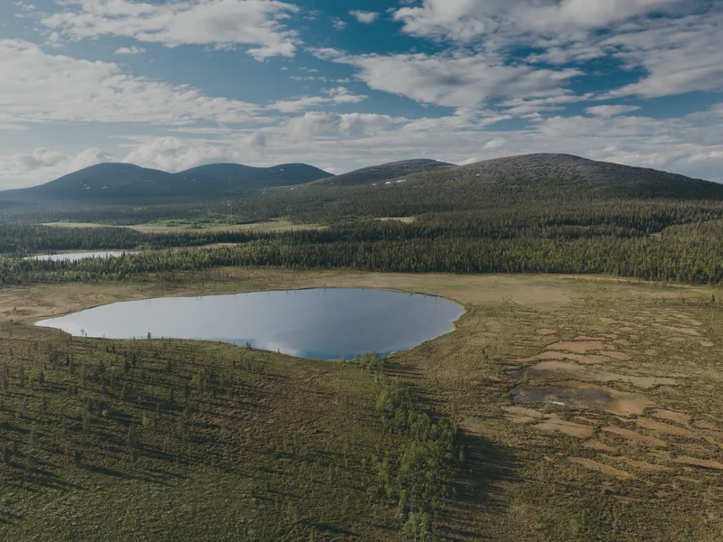 The Pallastunturi fells behind forest, bog and the small Hanhijärvi lake, seen from the air in June